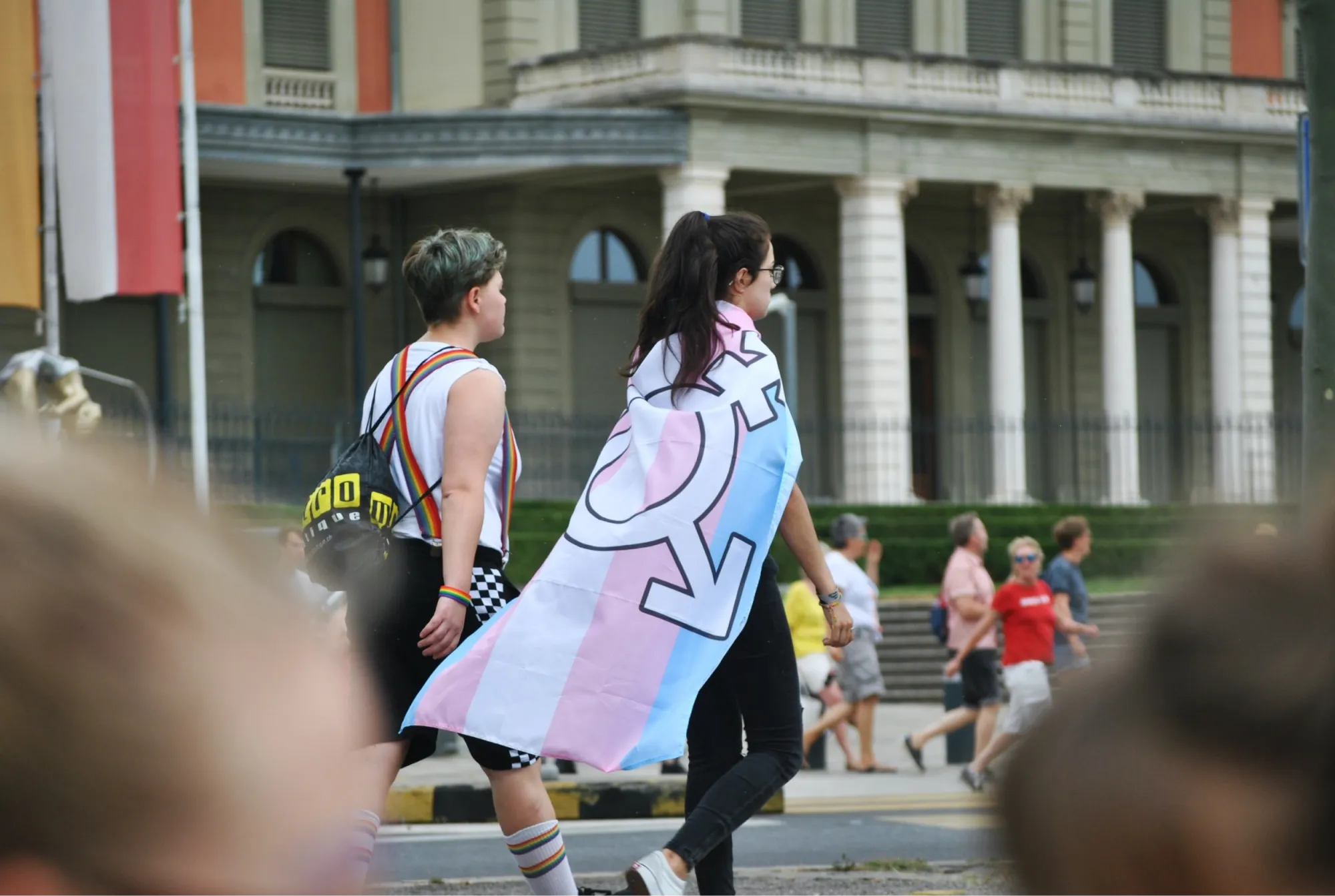 Menschen, die eine Strasse entlanggehen mit einer Flagge um die Schultern